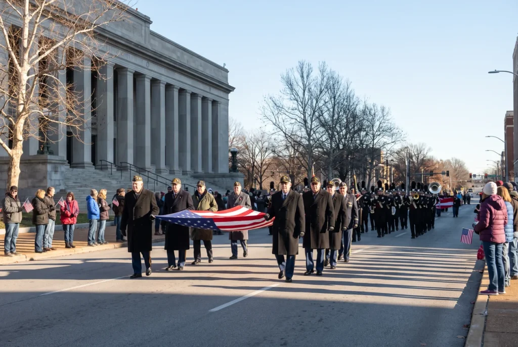 Veterans in unit ball caps marching toward Soldiers Memorial in downtown St. Louis on a cold clear November morning, spectators with small American flags on the kerb